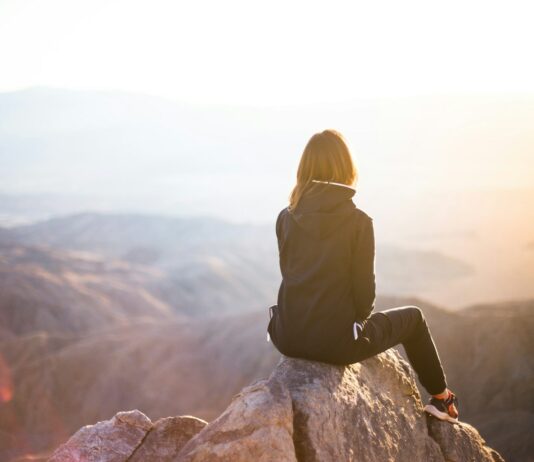 심리적 안정에 큰 역할을 하는 운동의 역할 person sitting on top of gray rock overlooking mountain during daytime