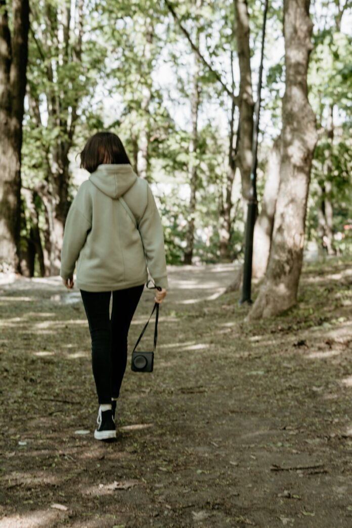 woman in green coat walking on pathway during daytime