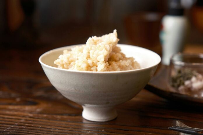 Photo by Seiya Maeda a white bowl filled with rice on top of a wooden table