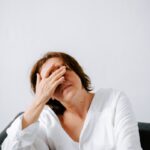 “만성피로, 단순 피로 넘어 ‘현대인의 질환’으로… 맞춤형 관리가 핵심” a woman sitting on a couch holding her hands to her face