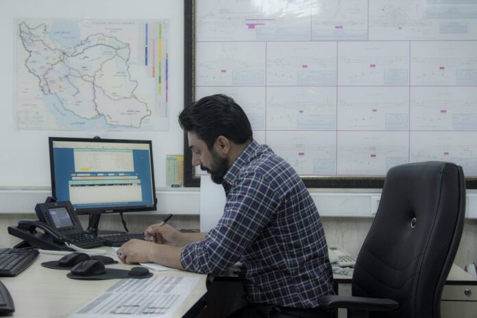 Photo by Javad Esmaeili a man sitting at a desk working on a computer