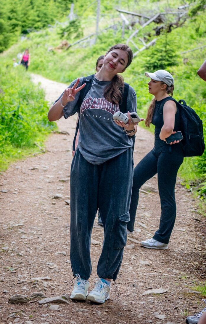 Photo by Timur Shakerzianov Young woman makes peace sign on a forest trail