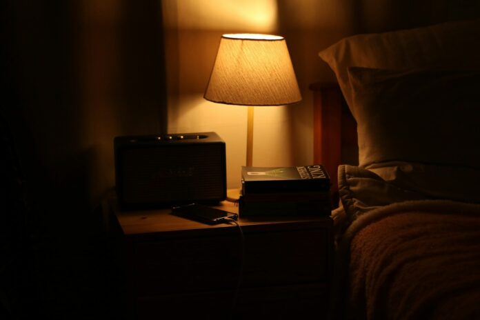 Photo by Alicia Christin Gerald A bedside lamp illuminates a nightstand with a radio.